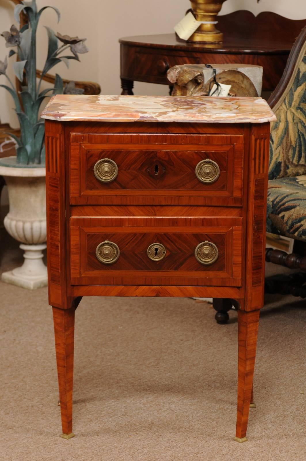The Louis XVI inlaid petite commode in kingwood with onyx top, two drawers with brass ring pulls, canted corners and tapered legs.