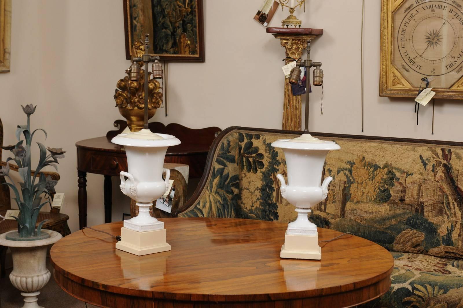 Pair of 19th century Continental Neoclassical style white porcelain urns, wired as lamps with two (2) light sockets.