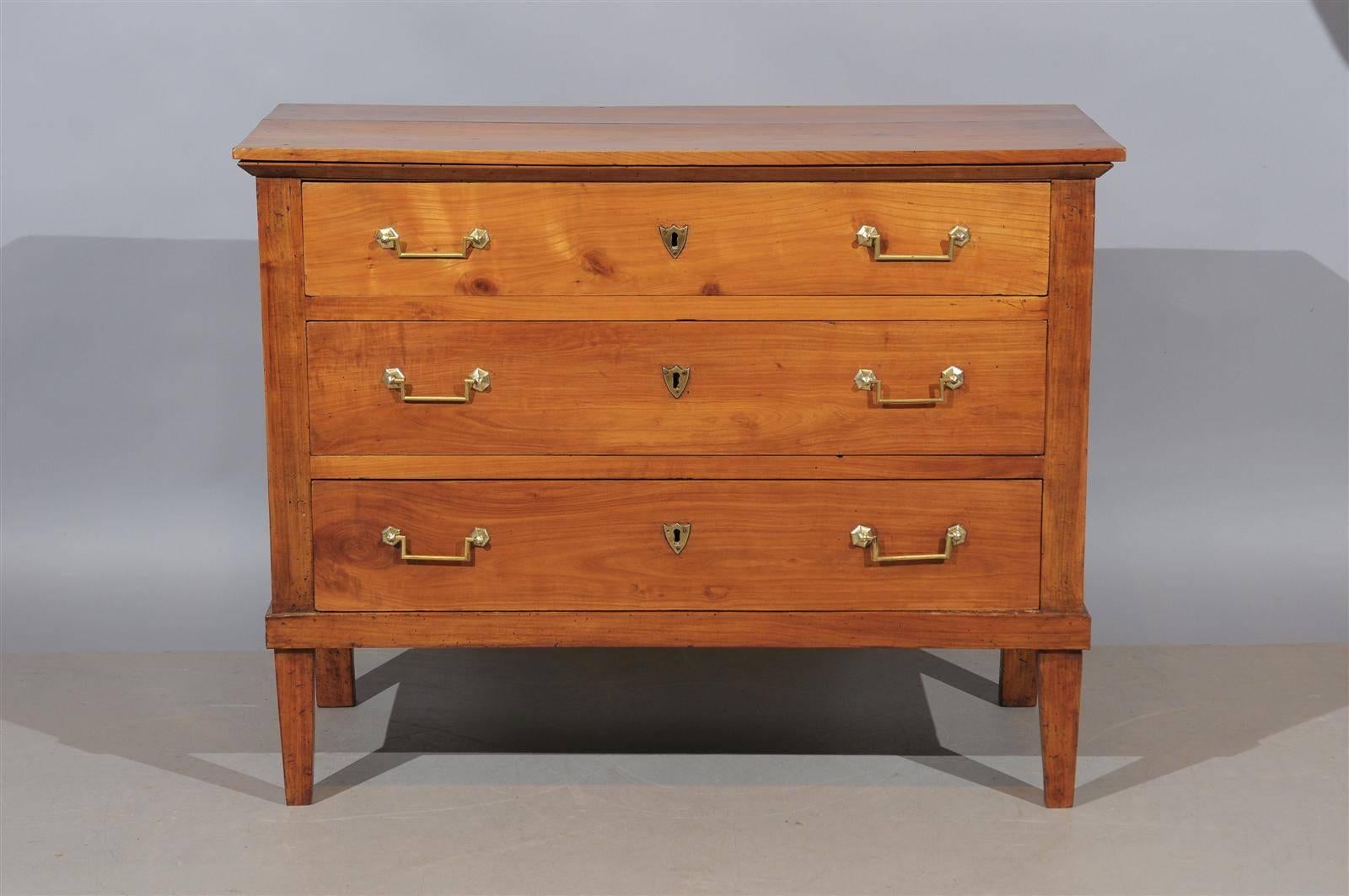 A Directoire fruitwood commode with three drawers and square tapering legs. 