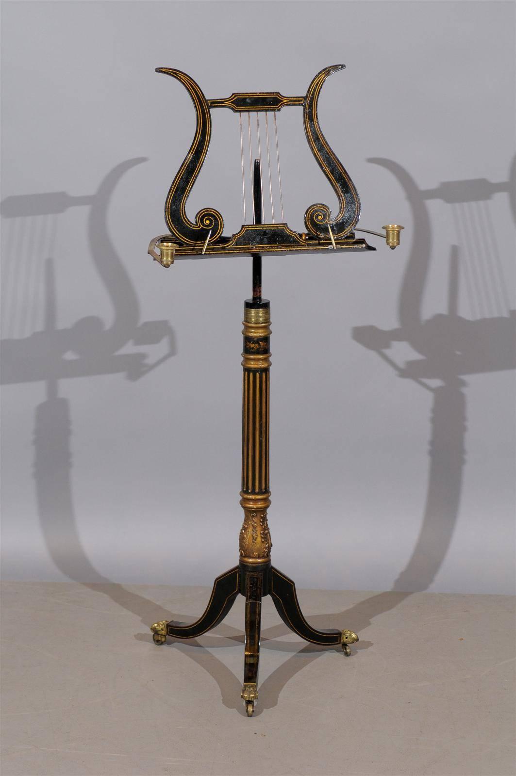 A 19th century English Regency ebonized and giltwood music stand with lyre shape and adjustable candle holders.