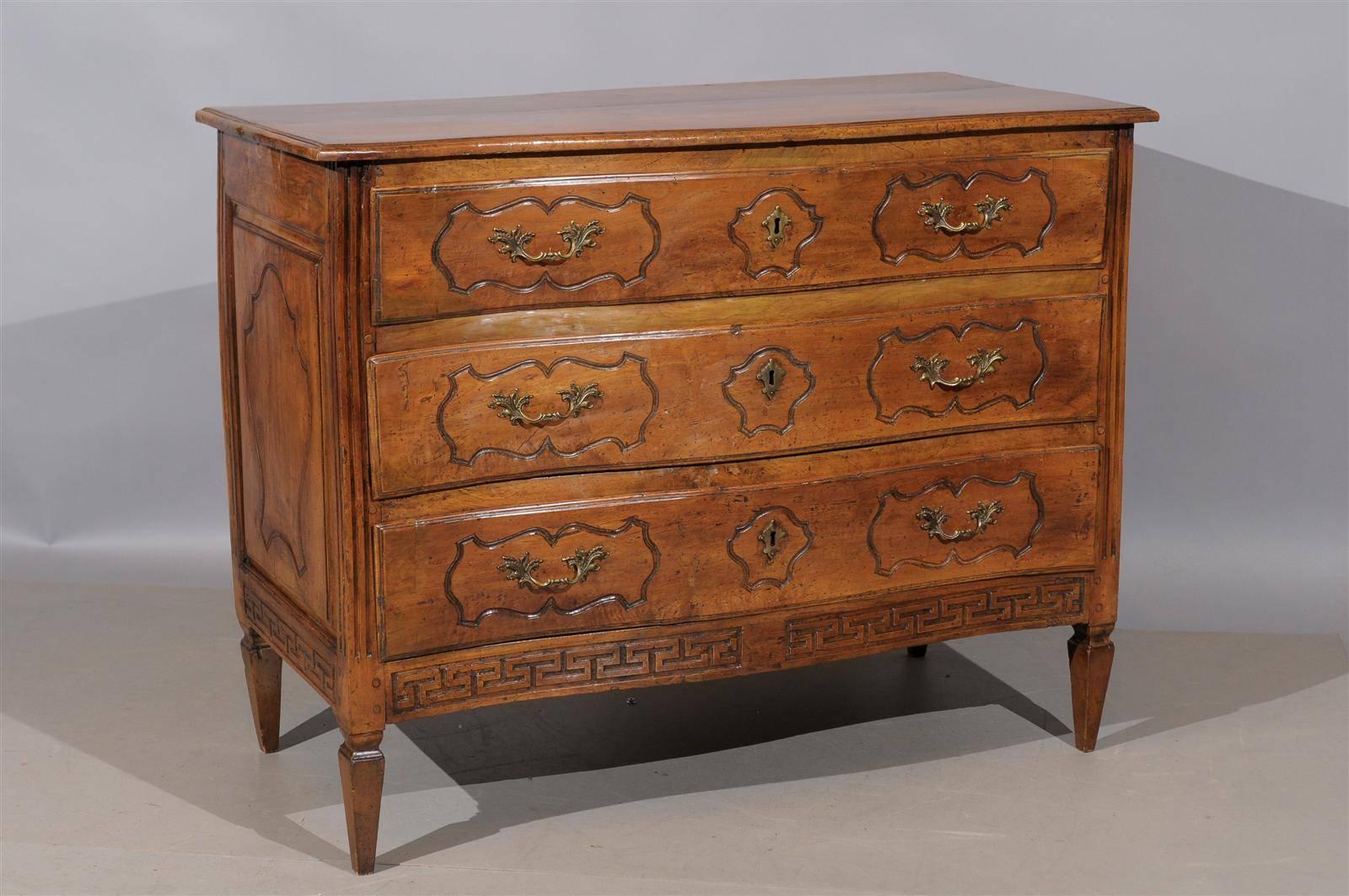 An Italian transitional walnut commode with serpentine front, three drawers and Greek key on apron with fluted sides and tapering legs.

