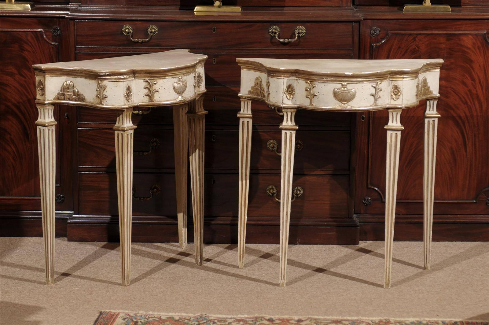 A pair of Italian painted and silvered Neoclassical consoles with urn detail and fluted legs. 

