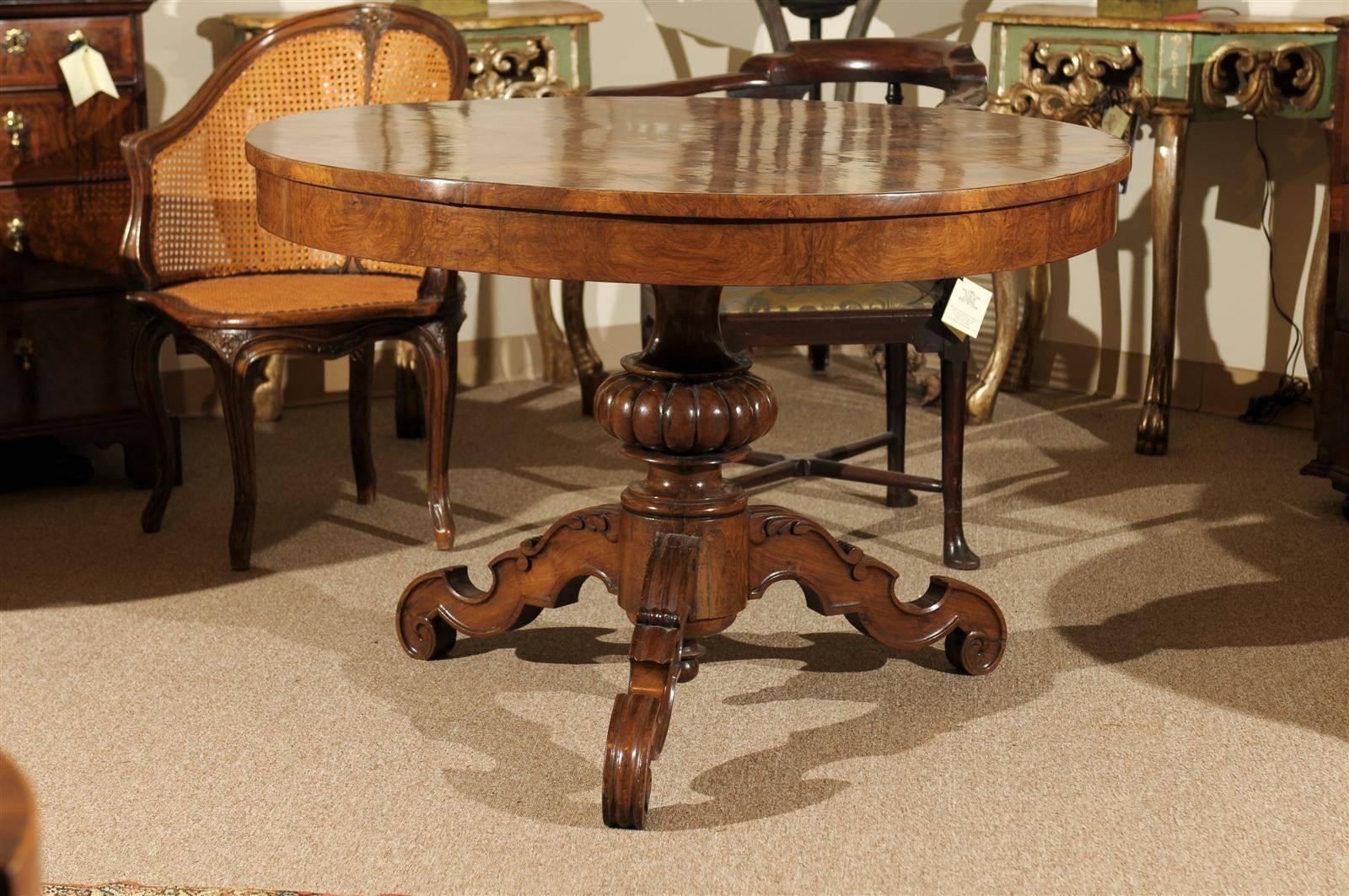 A burled walnut center table with carved tripod base.

