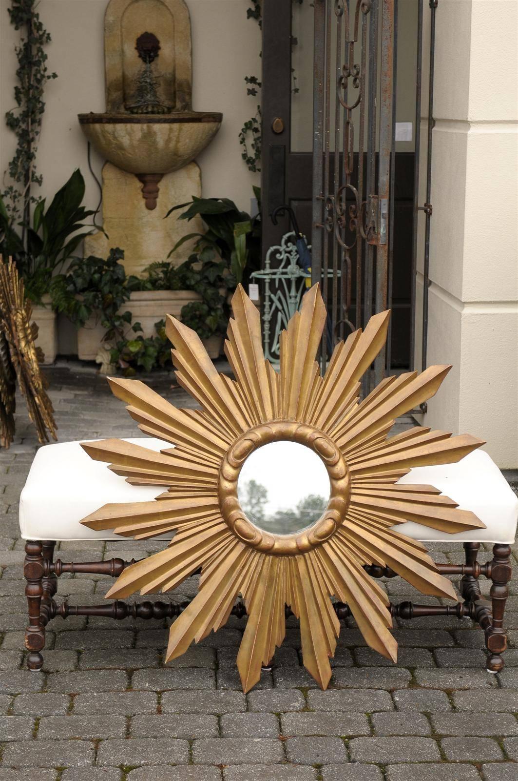 This large size French sunburst mirror from the mid 20th century features a small central circular mirror, surrounded by a carved molding. Spreading from there, neatly organized sunrays of various sizes send out joyous bright life. Its good