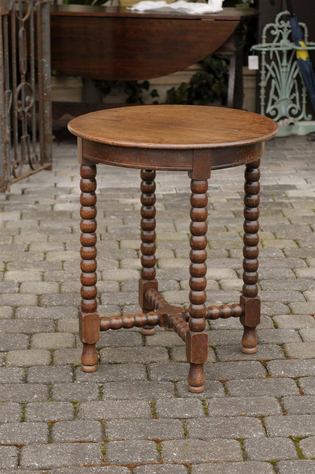 This French late 19th century side table features a round top with simple apron, over four bobbin legs, connected to one another with a bobbin cross stretcher. The table is raised on four small feet. This round French side table circa 1880 would be