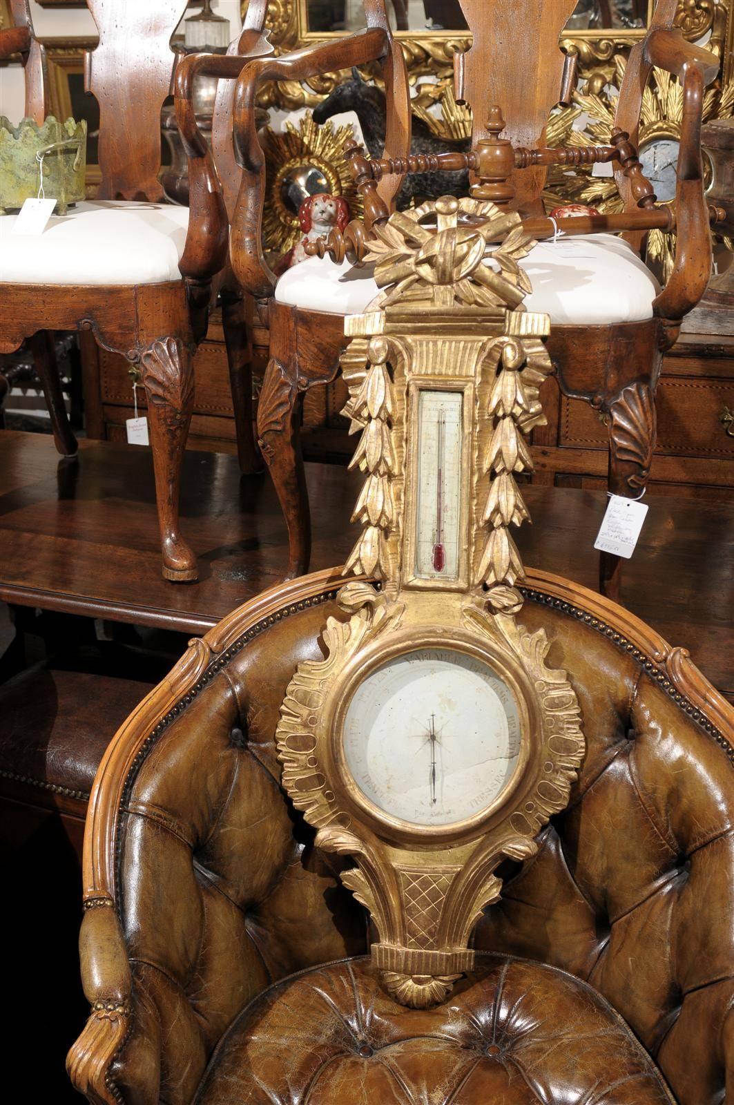 This exquisite French Louis XVI style mid 19th century giltwood barometer features a carved crest with quiver and foliage motif. In the lower section of the piece sits the barometer, nicely decorated with carved foliage in the surround while the