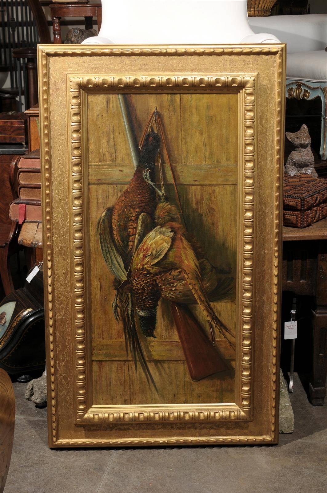 Vertical oil painting of gun and game in hand carved gilt wood frame.