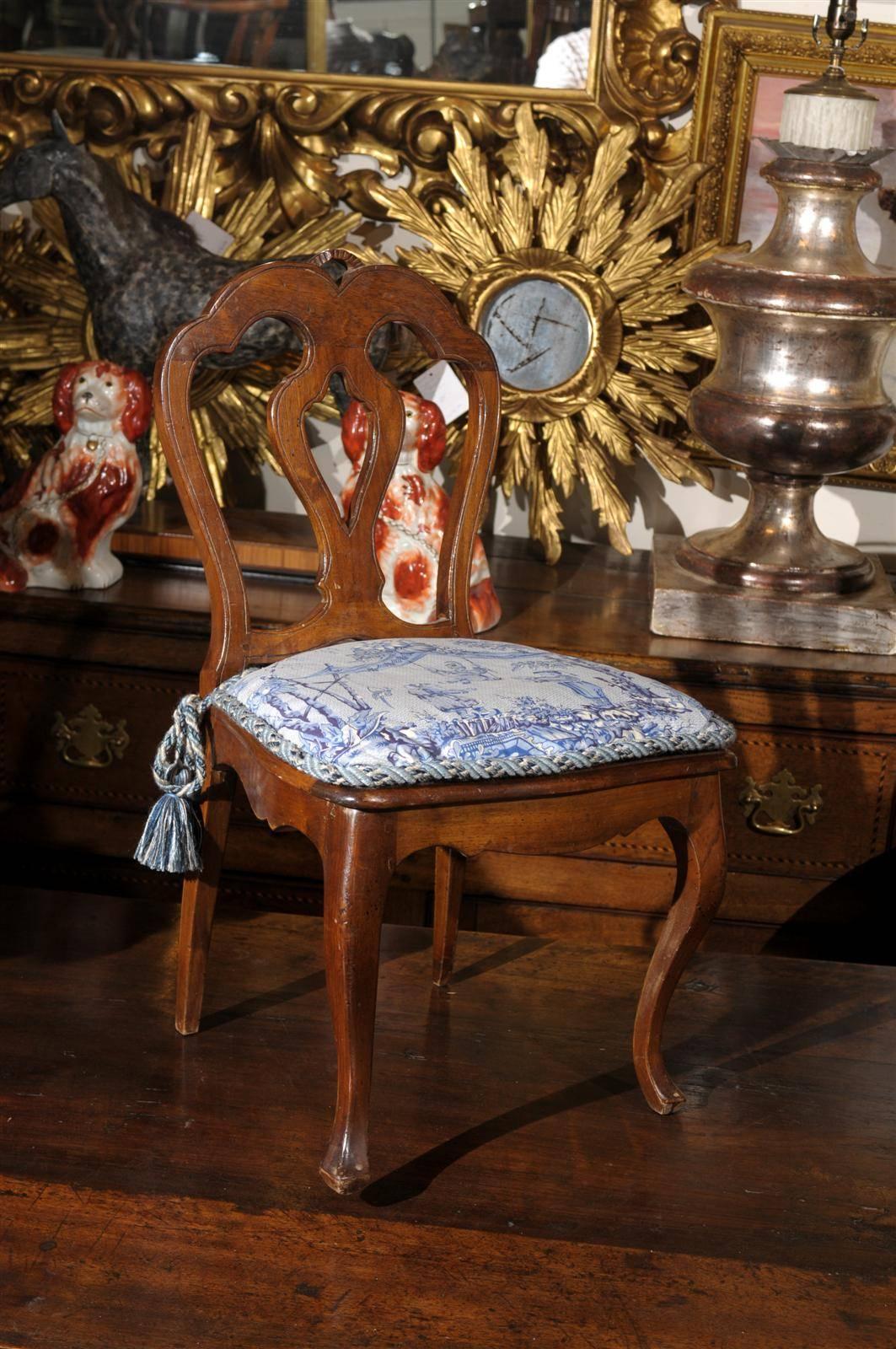 This French walnut child's chair from the 19th century features a slightly slanted and curved back with pierced splat. This small size side chair from circa 1860-1870 is raised on two cabriole legs in the front, reminiscent of the Louis XV era, and