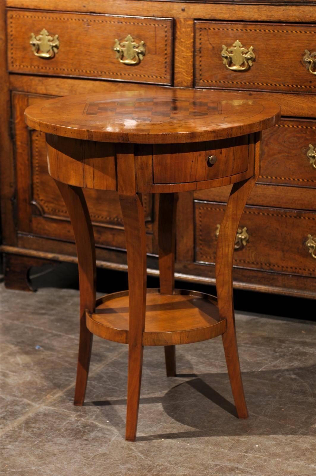 This petite Italian side table from the early 19th century features a round top decorated with cube parquetry inlay in the centre, surrounded by an exquisite marquetry of floral motifs. Below this lovely top is the circular apron with its single