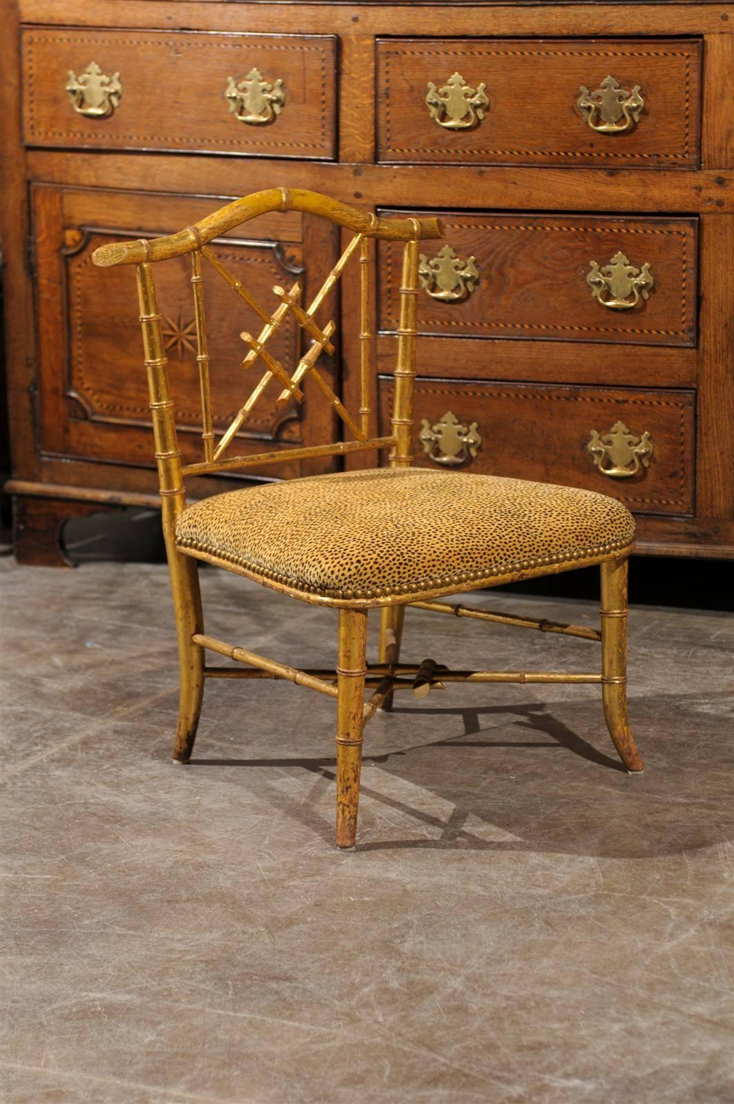 This French Chinese Chippendale style stool with back is from the mid 20th century and features a giltwood faux-bamboo armature. The back, made of geometric motifs typical of the Chinese Chippendale style, is topped with a slightly arched rail. The