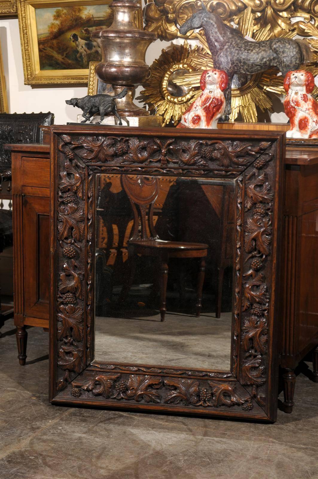 This German Black Forest mirror from the late 19th century features a rectangular frame with skillfully carved foliate motifs on the surround. The molding closest to the mirrored section is also discreetly carved, giving a visual pause before the