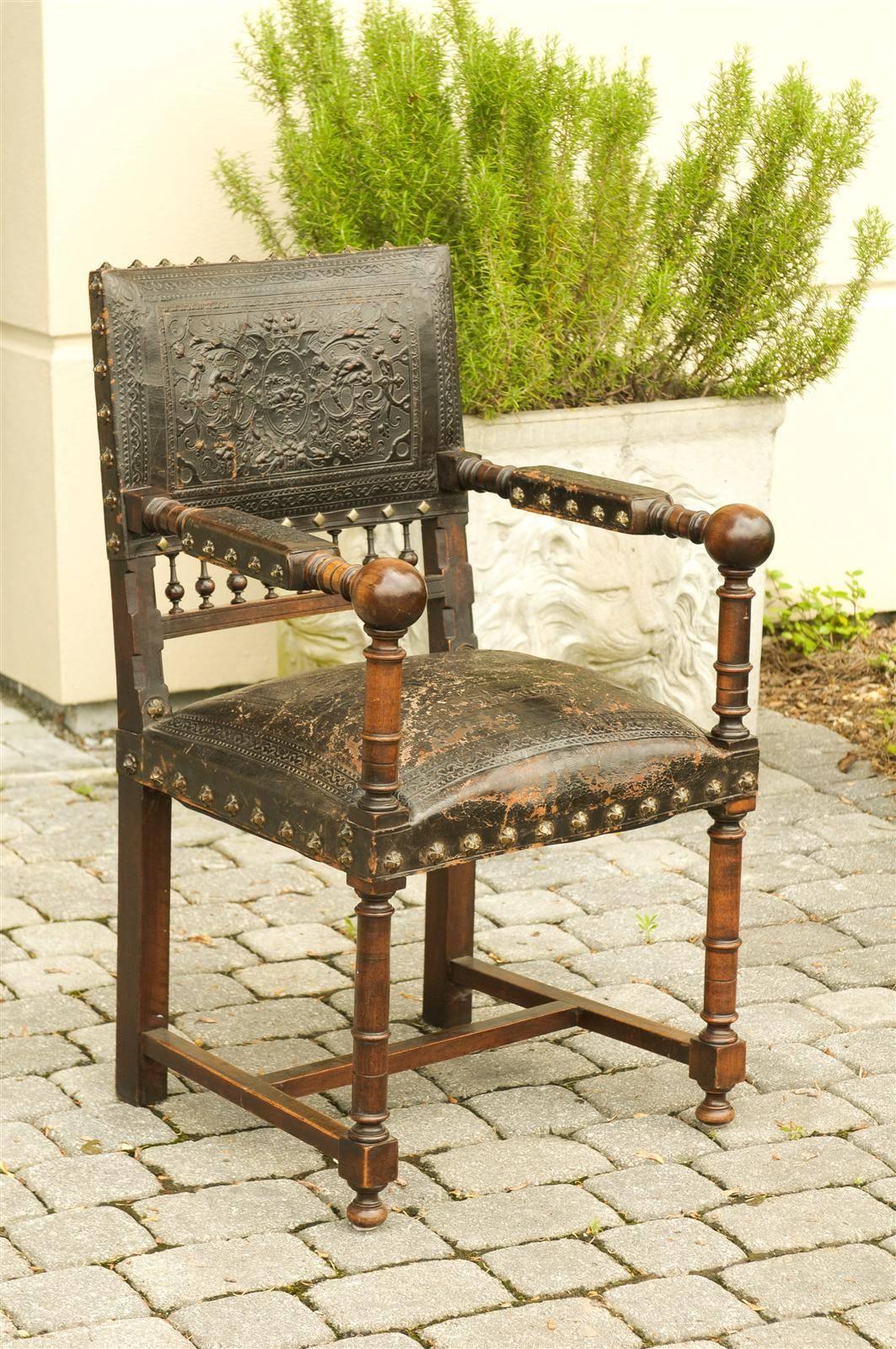 A French wooden armchair with leather upholstery from the turn of the century (19th-20th). This French wooden chair from circa 1890-1910 features an exquisite original black leather embossed back and seat, as well as partially upholstered open arms.