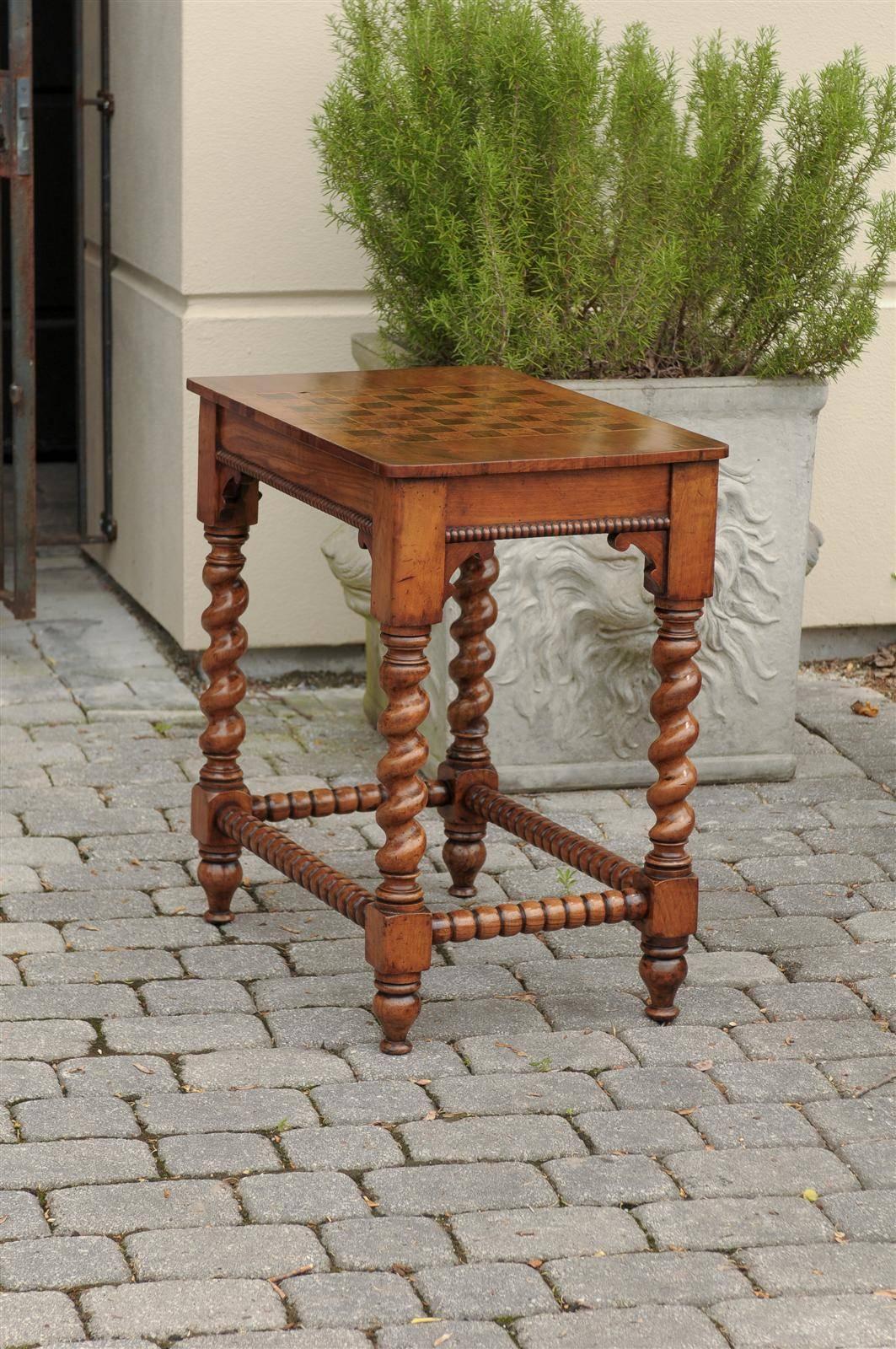 A 19th century English barley twist leg side table with checker board inlay top. This English small size side table from circa 1880 features a checker board inlaid top with a single lateral drawer. The table is adorned with wooden beading on all