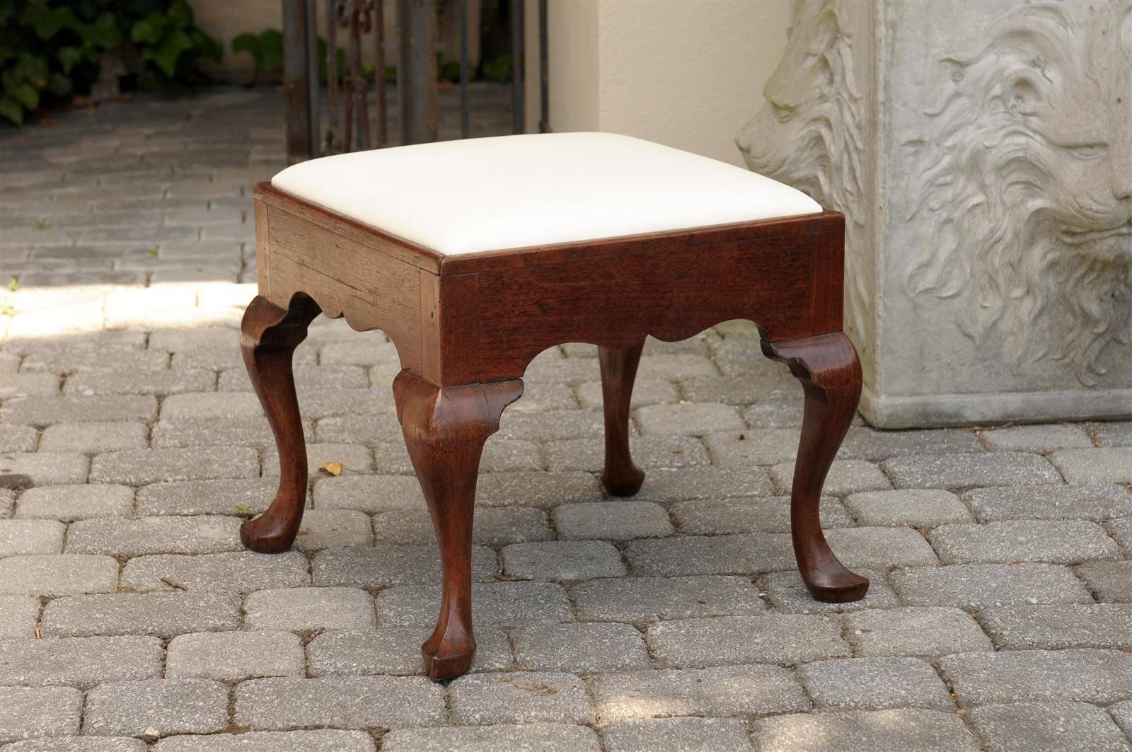 An English stool or ottoman with muslin covered seat from the 1860s.  This elegant English ottoman or stool features a wood square structure over four cabriole legs with pad feet and shaped apron. The muslin upholstery is new. In England, the period