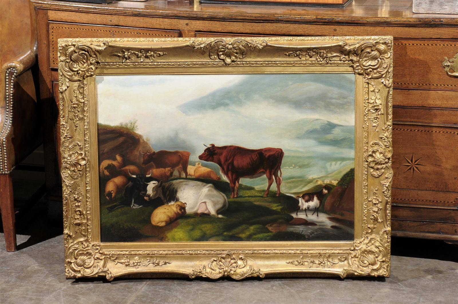 A large size English late 19th century framed pastoral oil painting depicting cattle, sheep and goat in a landscape. The center of the composition is occupied by a brown cow that is proudly standing on the luscious green grass and seems to be