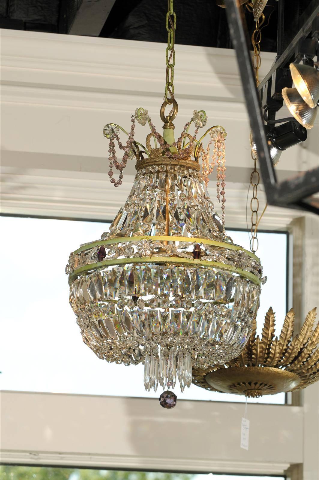 This petite French crystal chandelier from the mid 20th century features a lovely basket shape. Reminiscent of the Empire taste, the chandelier is made of a metal double ring adorned with diamond shaped crystals of amethyst color. The crystals give