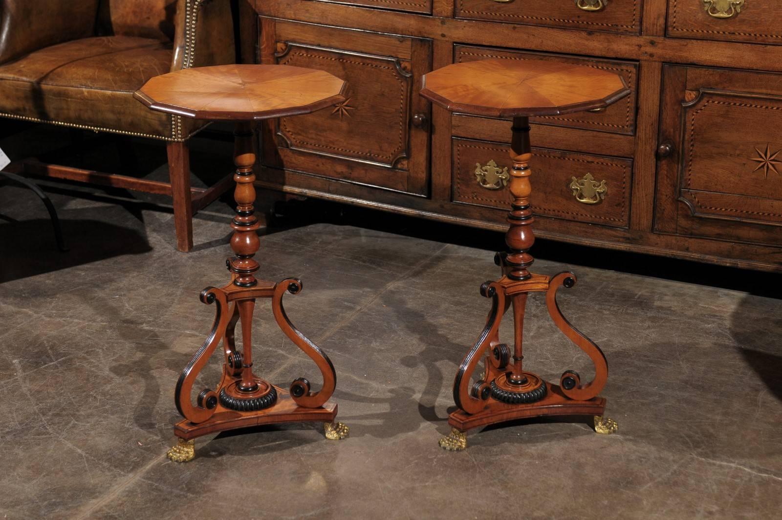 A pair of early 19th century English period Regency parcel-ebonized wooden side tables featuring a dodecagon molded top over a baluster-turned support with ebonized rings. Each table is raised on a triangular base with concave sides below three