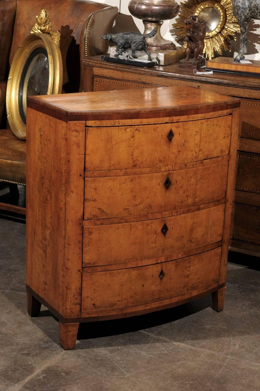 A mid 19th century birch Biedermeier bowfront chest of four drawers featuring a rectangular top with a banded inlay of darker wood on three sides running on both the rectangular top and the upper part of the top rail. Separated by crossbars, each