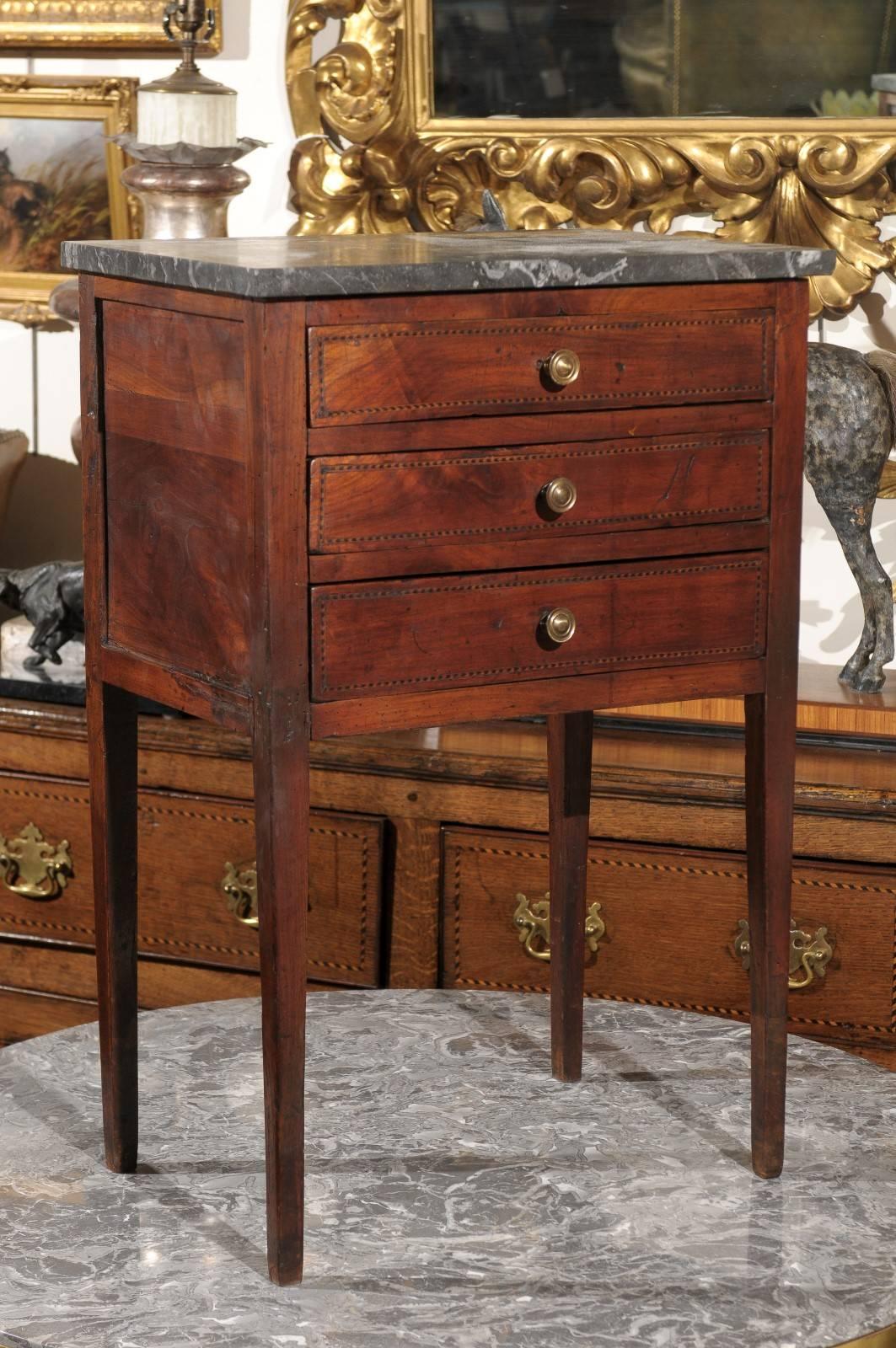 A petite French mid-19th century three-drawer commode. This French commode from circa 1830 features a rectangular grey veined marble top over three nicely hand-carved dovetailed drawers with delicate banding and round brass pulls. This delicate