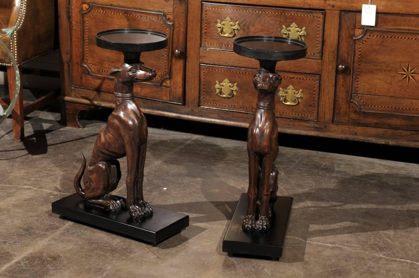 Pair of carved wood greyhound side tables on recent bases.  This pair of 19th century wood carved greyhound (or whippet) side tables are mounted on recent black rectangular bases. Each greyhound is sitting proudly, propped on its front legs and