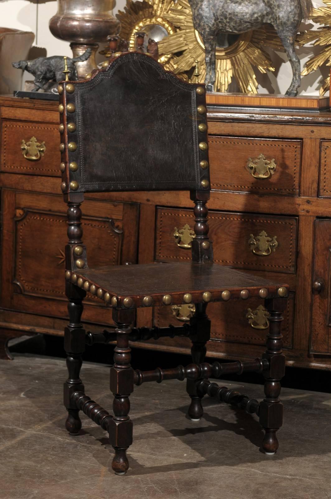 Early 20th century English leather side chair. This English chair from circa 1920 features a leather upholstery with exquisite brass nailheads around the back and seat. The slightly slanted back has a bonnet type crest rail flanked with two brass