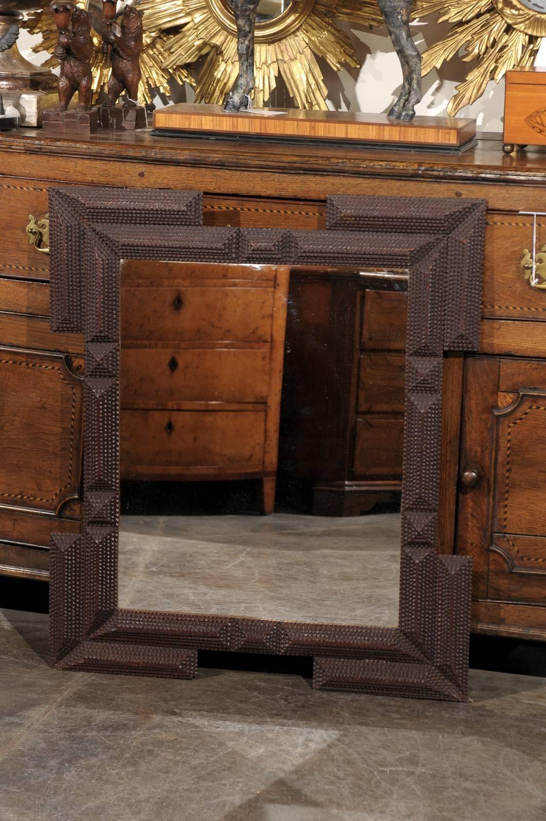 A French Tramp Art carved wood mirror from the turn of the century (late 19th-early 20th century). This French Tramp Art mirror from circa 1900 features a central rectangle, doubled in each of its corners by a motif mimicking the frame. The ensemble