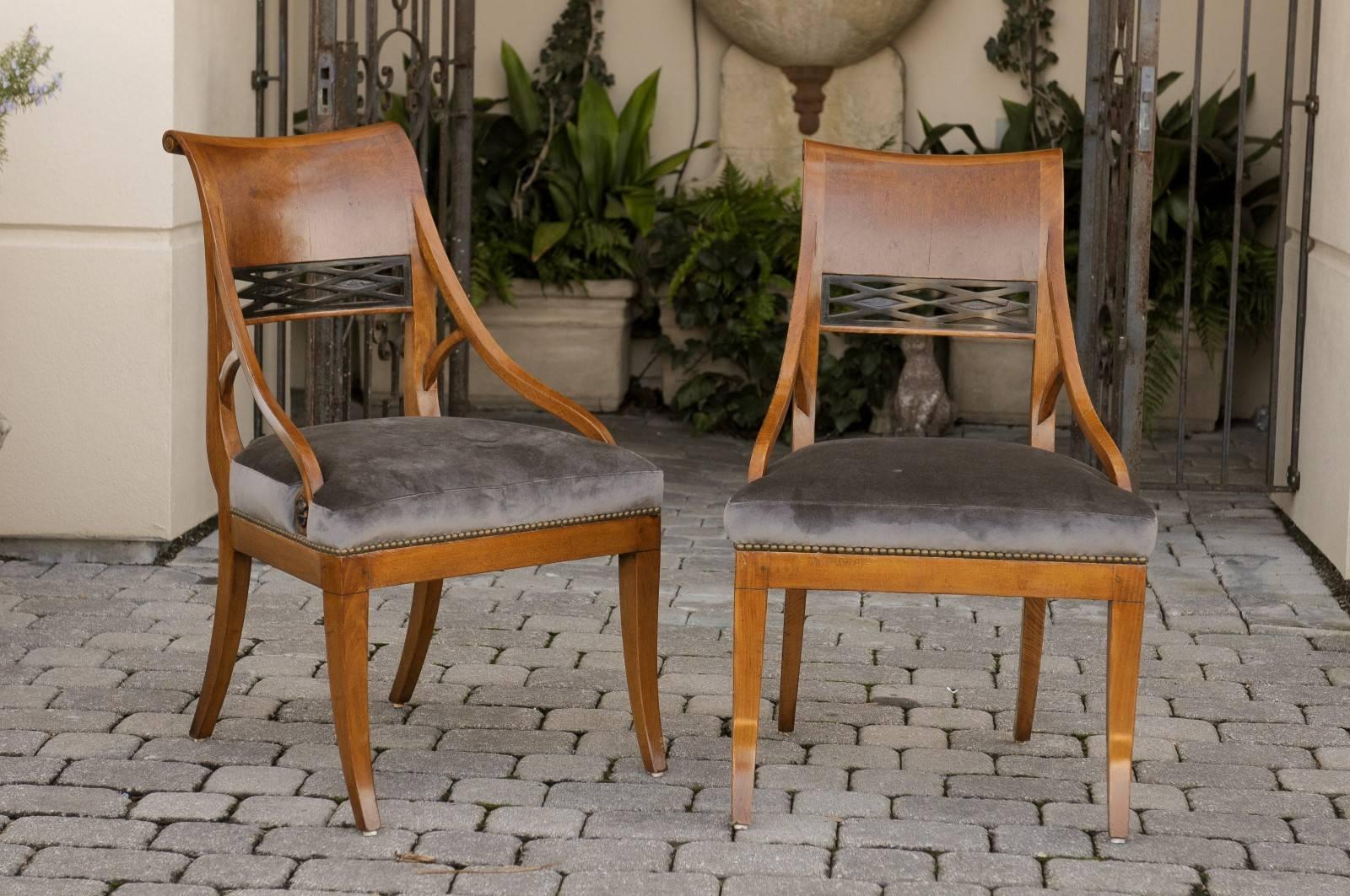 A pair of Austrian, 19th century Biedermeier side chairs. This pair of Biedermeier birch side chairs from circa 1840 features a scrolled back with partially pierced ebonized diamond patterns. The chairs are raised on four saber legs, typical of the