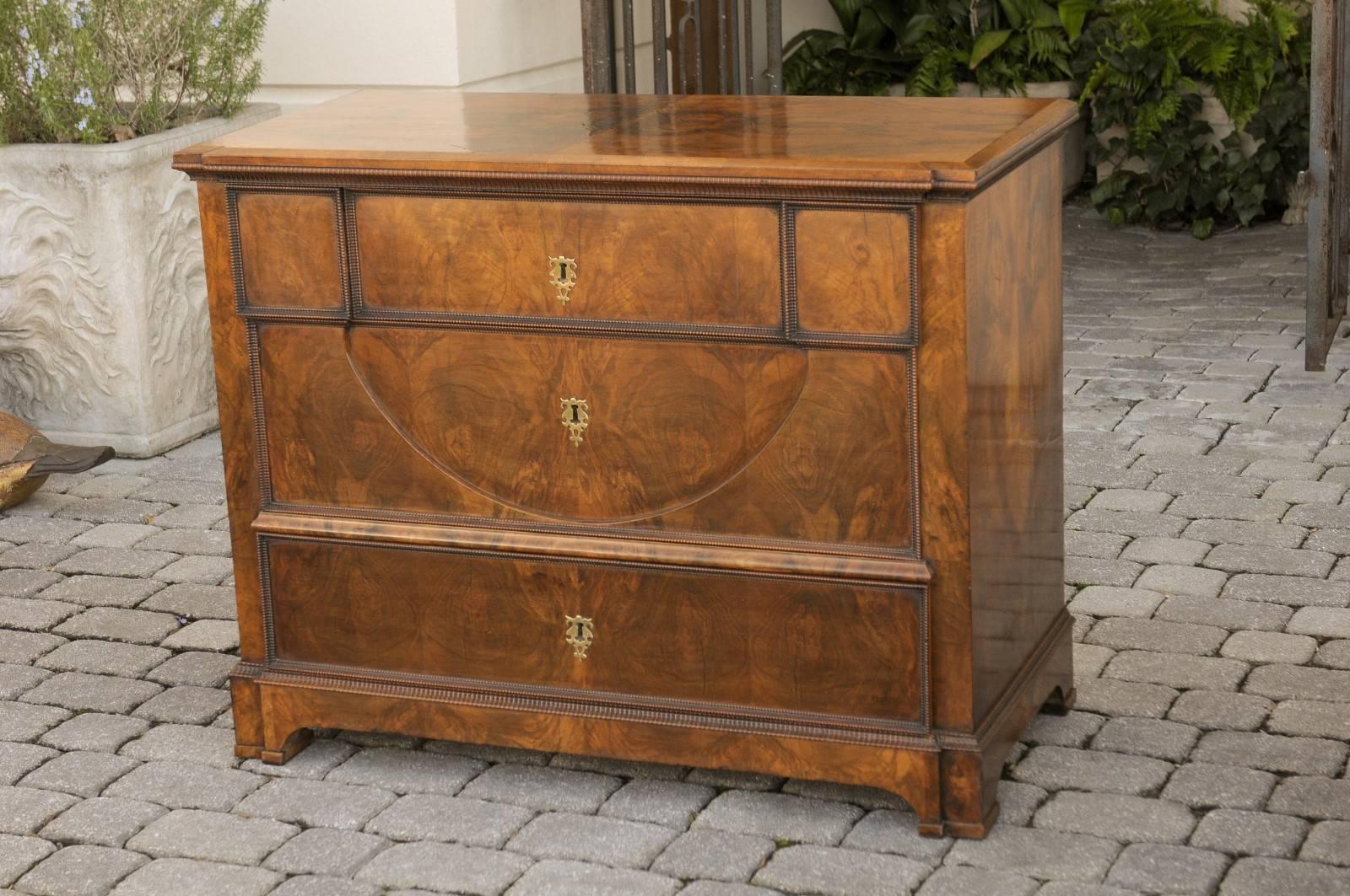 An Austrian mid-19th century Biedermeier commode. This Austrian wooden chest from circa 1840 features three drawers with central escutcheons. In typical Biedermeier fashion, the top drawer is adorned with geometrical motifs with a nicely carved