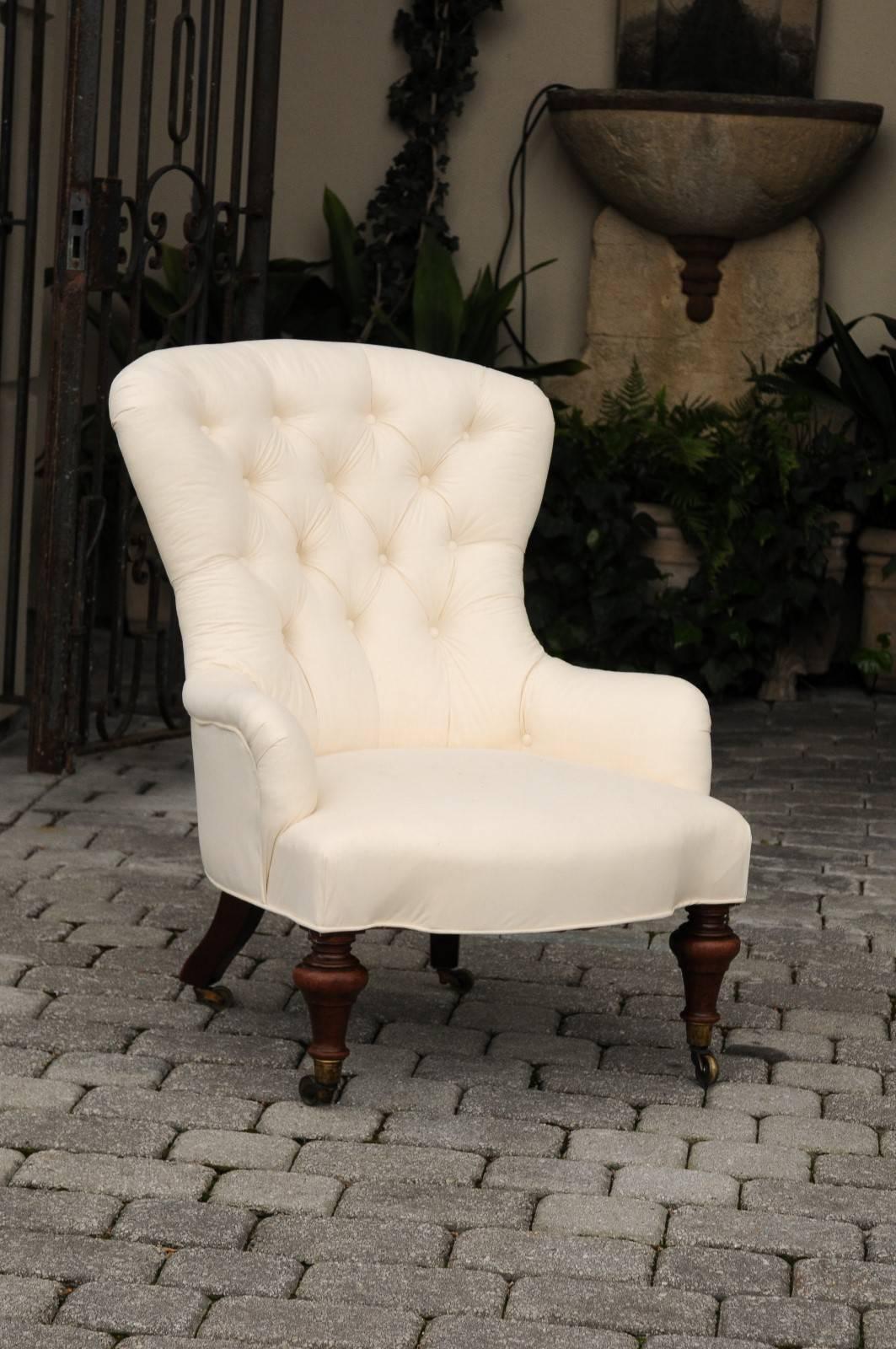 This English slipper chair from the late 19th century features a tufted upholstered back with an upholstered seat and outswept arms. This fanback chair is perfect for welcoming the sitter comfortably. The chair is raised on four William IV style