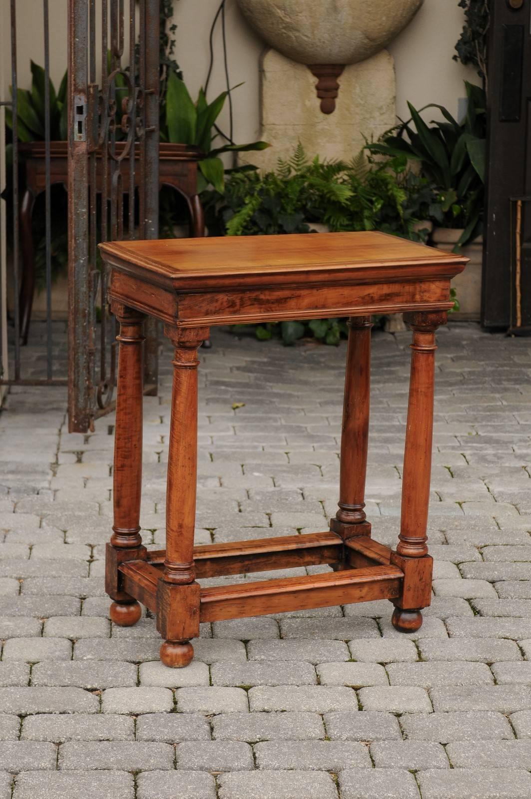 Cette exquise table d'appoint en bois fruitier de style Empire français du milieu du siècle présente un plateau rectangulaire soutenu par quatre colonnes en bois de style dorique, avec un renflement caractéristique de l'entasis, une forme légèrement