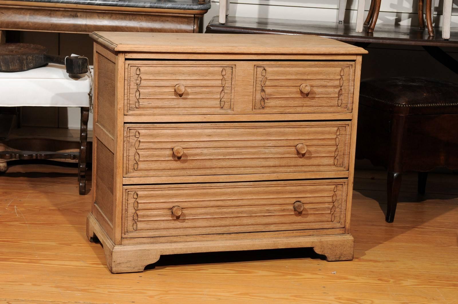 This English oak chest from the late 19th century features a rectangular top with rounded edges over three drawers. The top drawer's decoration gives the illusion of two drawers, but is in reality a single drawer segmented into two halves. The decor