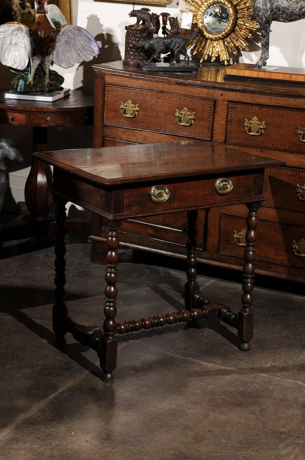 An English oak late 18th century Georgian side table with bobbin legs and cross stretcher. This table features a two plank top with beveled edges and a single drawer supported by four turned legs in a bob and stop pattern with simple bun feet. The