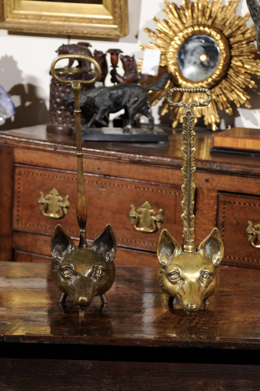 Two tall English turn of the century (19th-20th) brass fox head doorstops. These wonderfully cast fox heads show great character. They are hollowed out and raised on three slender feet. Both doorstops feature a tall handle that makes for easy moving