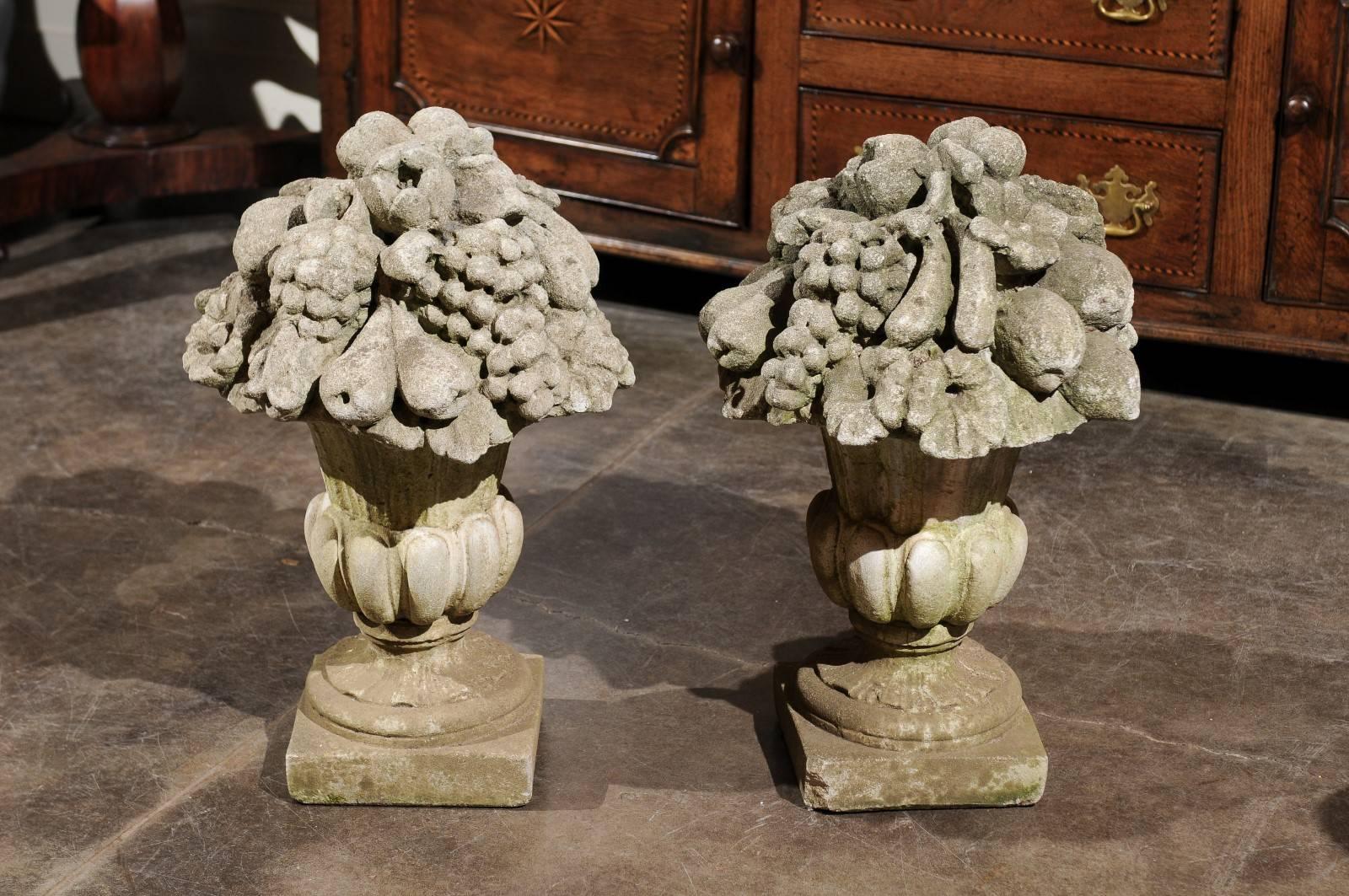 This pair of French stone sculptures from the early 20th century features two Médicis vases with gadroon decor on a square base. This exquisite pair of early 20th-century French stone sculptures showcases two Médicis vases, each richly adorned with