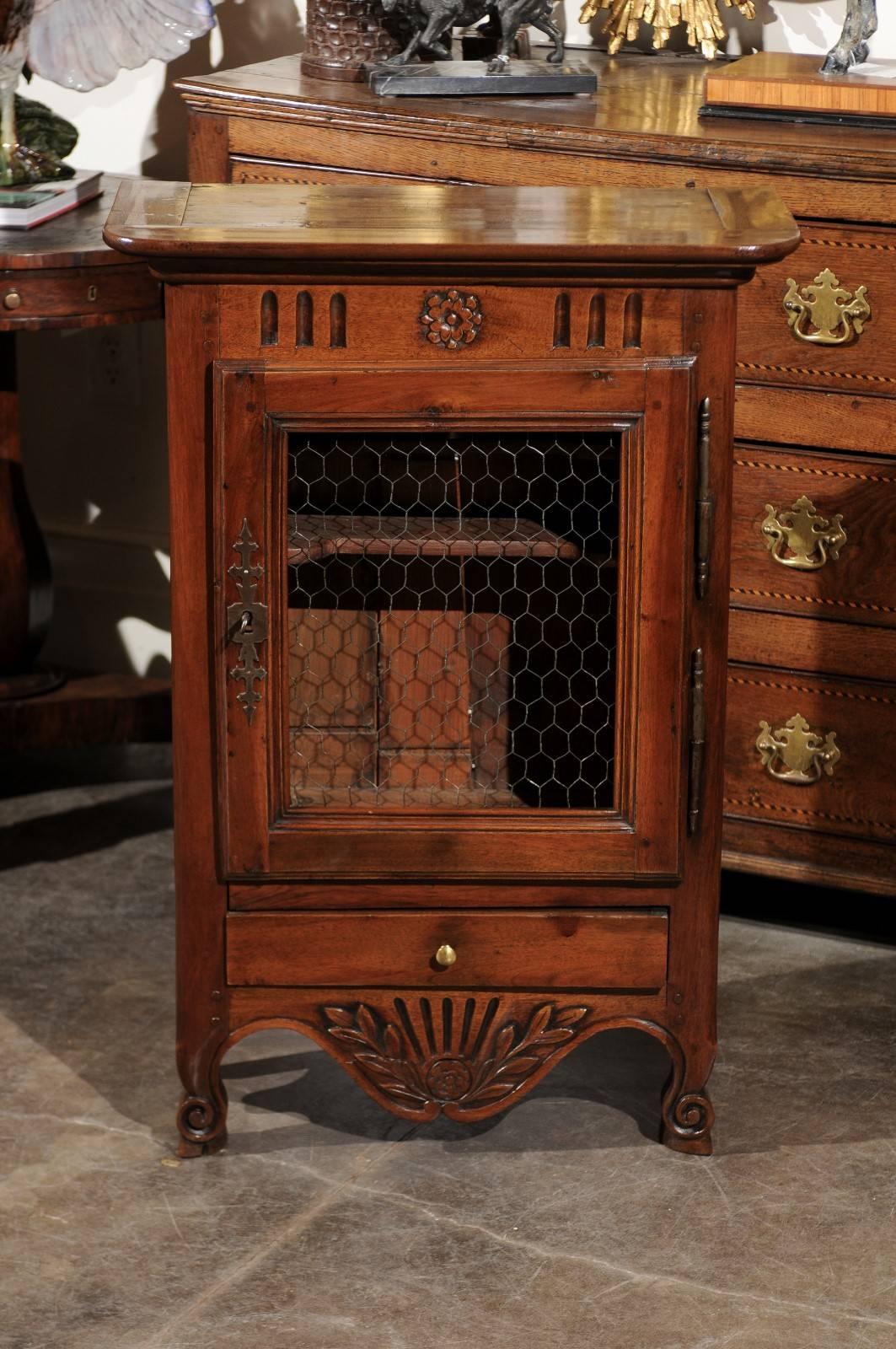 A French walnut small size cabinet from the mid-19th century. This French narrow cabinet features a door with chicken wire over a single lower drawer. 
The door opens to a storage area with two upper shelves. In the lower section, a single drawer