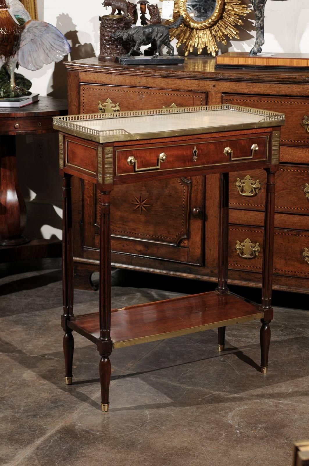 This elegant English Regency period console side table from the early 19th century features a rectangular white marble top surrounded by a delicate pierced brass gallery. The front is decorated with a single drawer with linear bail handles and