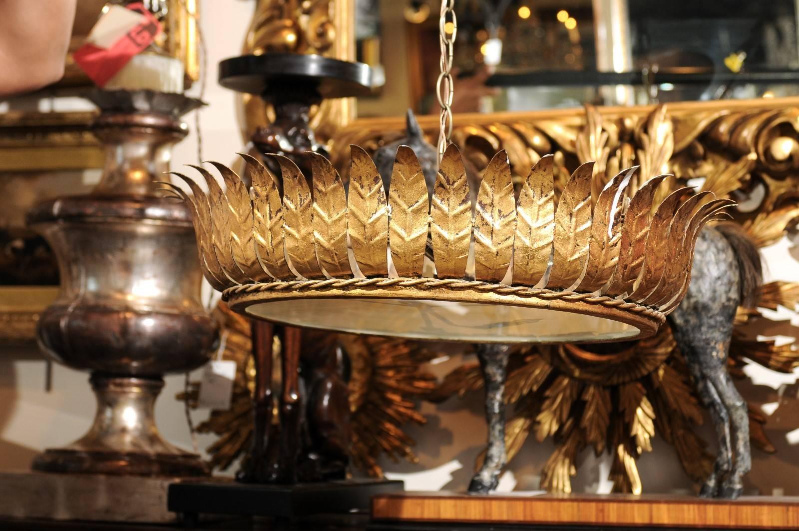 A Spanish mid-20th century crown semi-flush pendant of gilt metal with frosted glass. This Spanish gilt metal chandelier is adorned with leaf motifs all the way around, secured by an elegant twisted gold braiding on the bottom. The two lights sit