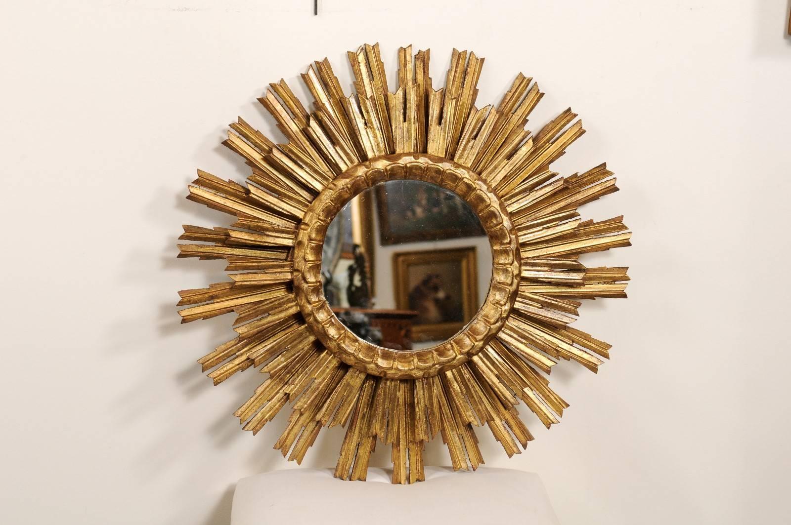 This French giltwood sunburst from the mid-20th century is made of a small central clear mirror, surrounded by a carved molding and double layered sunrays. While it can be difficult to find sunburst mirrors in good condition due to the fragility of