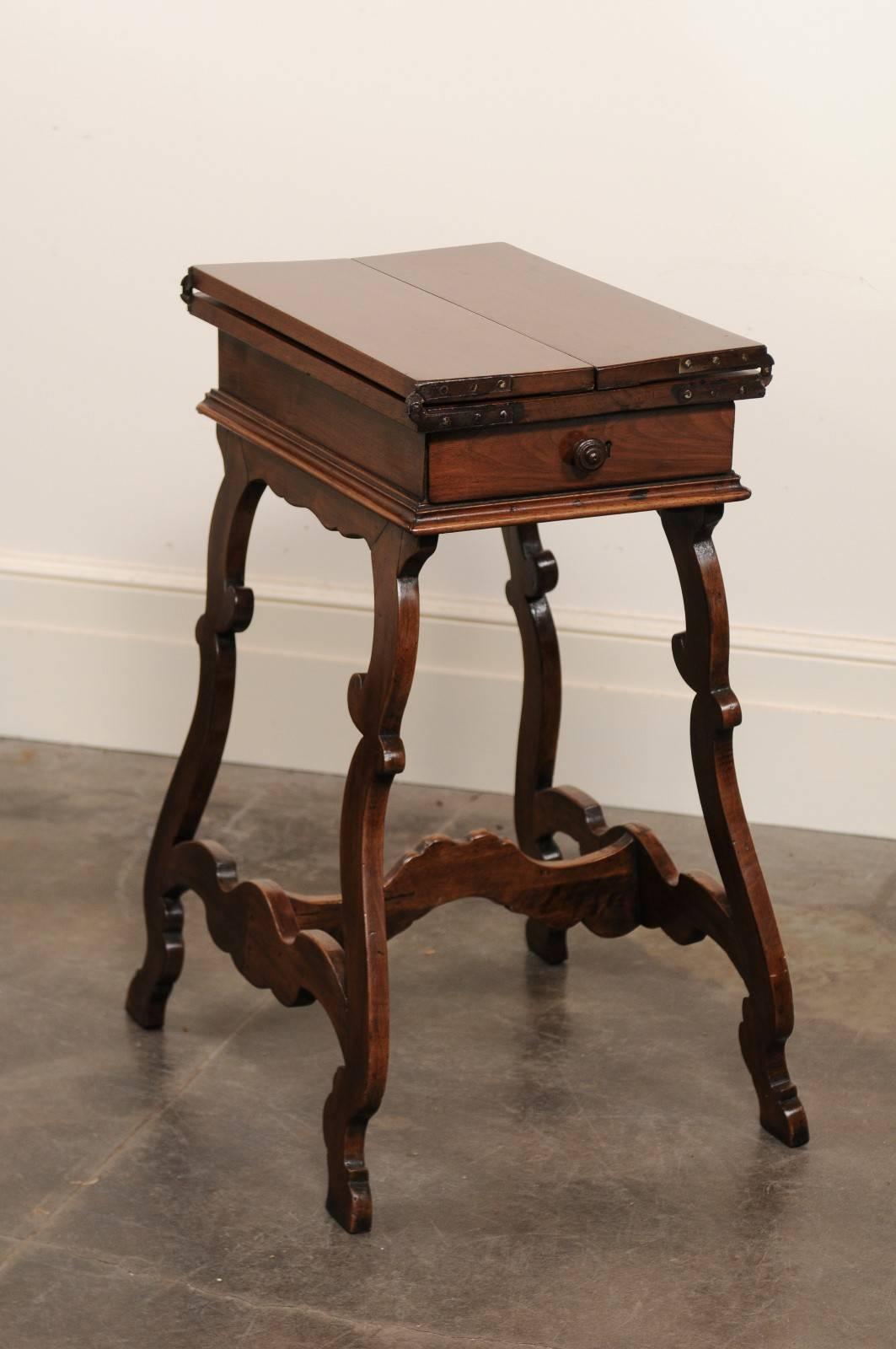 This Italian walnut side table from the early 19th century features an exquisite rectangular top that unfolds to reveal two small leaves, beautifully decorated in the corners and secured with brass hinges. This top sits above a single dovetailed