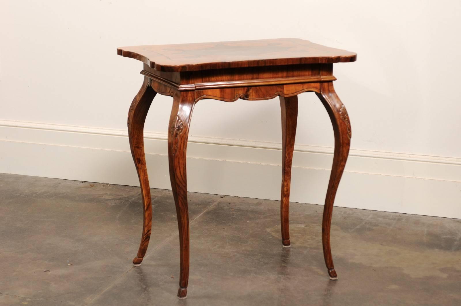 This spectacular Italian mid-19th century side table features an exquisite profiled and inlaid top with burl walnut over a carved apron. This apron is adorned in its center with a molding that camouflages the single drawer and gives perfect harmony