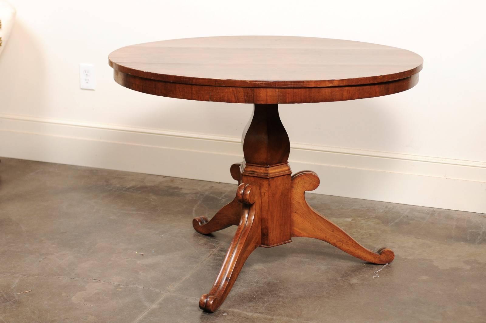 This French late 19th century burl walnut oval pedestal table features a radiating veneered top over a carved hexagonal pedestal with tripod base. The three fluted feet of this circa 1880 table are decorated with simple volutes. The veneered top of