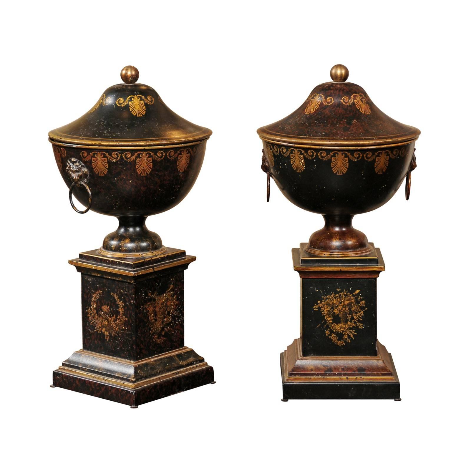 Pair of French 1920s Tole Black Tole Urns on Pedestals with Gilded Accents