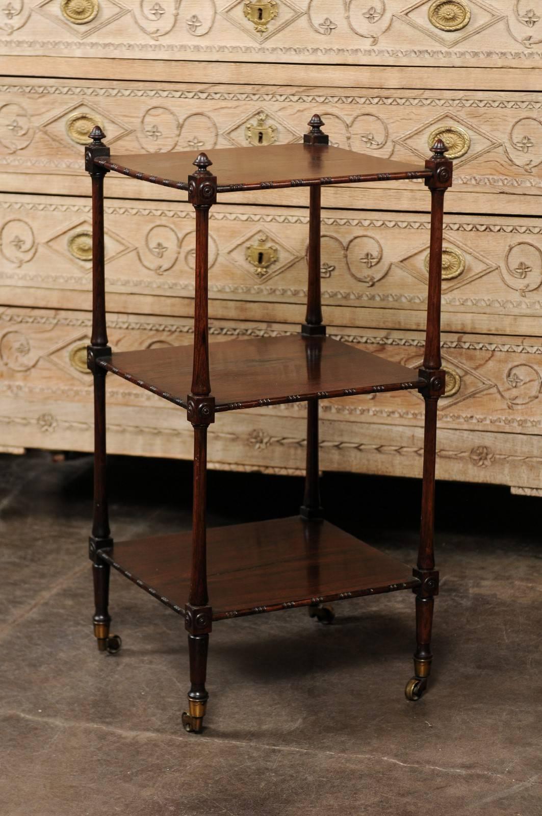 Questo carrello a gradini in legno di palissandro inglese della metà del XIX secolo presenta tre ripiani rettangolari con bordi intagliati su quattro lati, fissati all'interno di quattro eleganti montanti laterali. I pali sono sormontati da