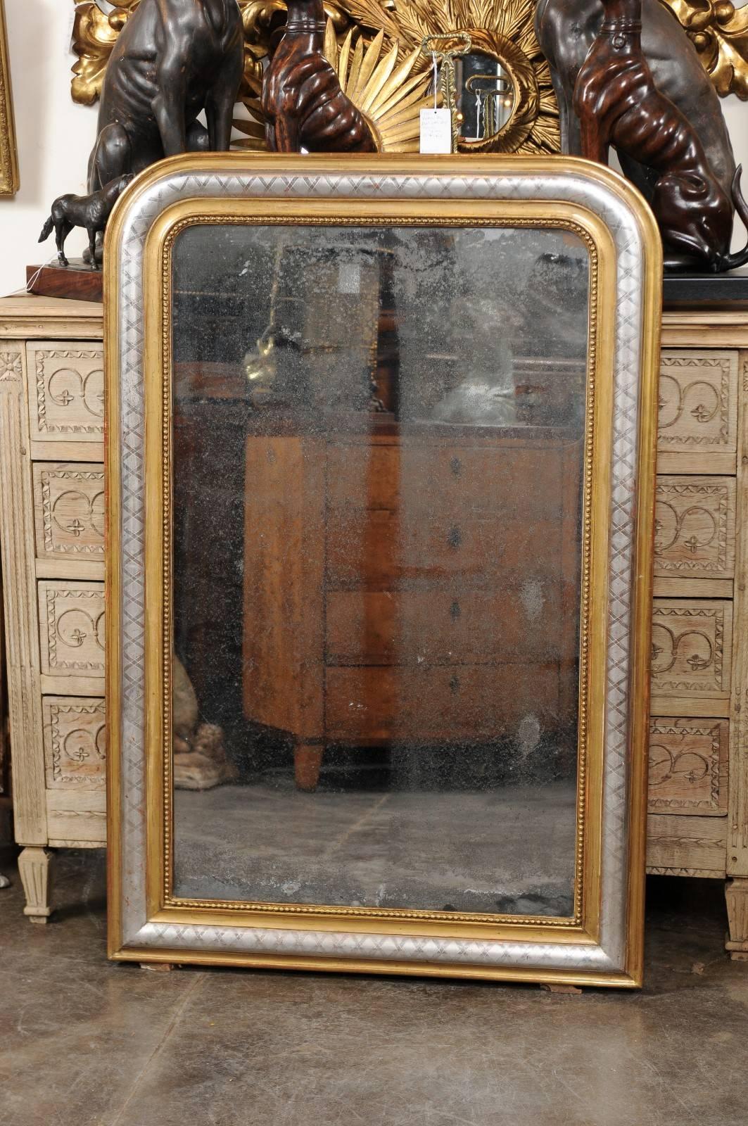 This French gold and silver Louis-Philippe mirror from the turn of the century features the typical rectangular shape with rounded corners at the top. The outer frame, made of a simply carved concave molding, is followed by a nicely contrasting