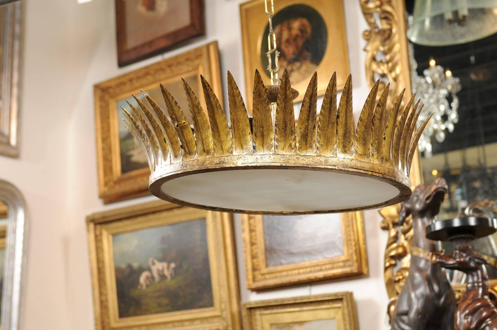 This vintage Spanish gilt metal chandelier with frosted glass is decorated by a crown of leaves curving vertically from the a simple frame that supports the glass and hardware. This elegant chandelier features four lights secured by a center