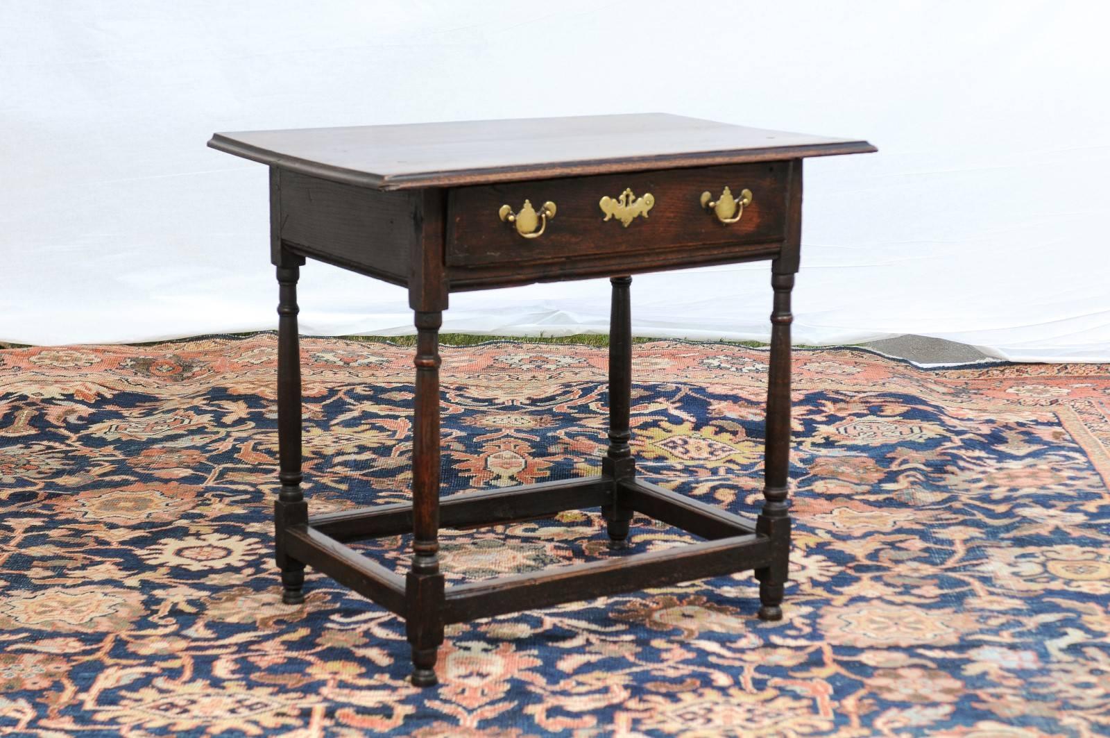 This English oak side table from the late 18th century features a two-plank rectangular top with beveled edge over a single drawer. This drawer is adorned with brass hardware and bail handles. The table is raised on four simple yet elegant Doric