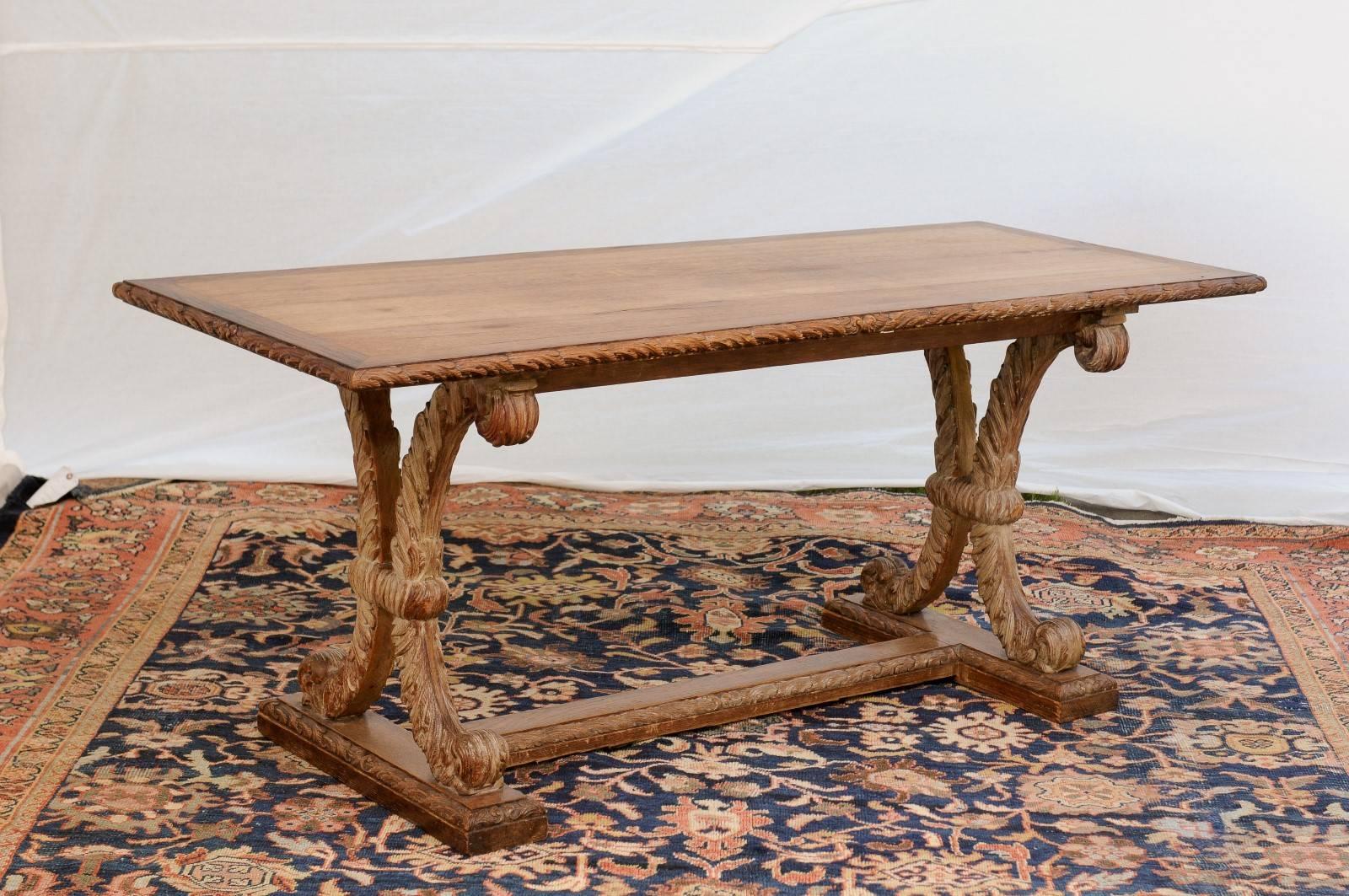 This French sofa table from the turn of the century features a rectangular top surrounded by a delicately carved molding. The top is made of three long planks secured by four wooden strips decorated with carved foliage molding. The top sits on an