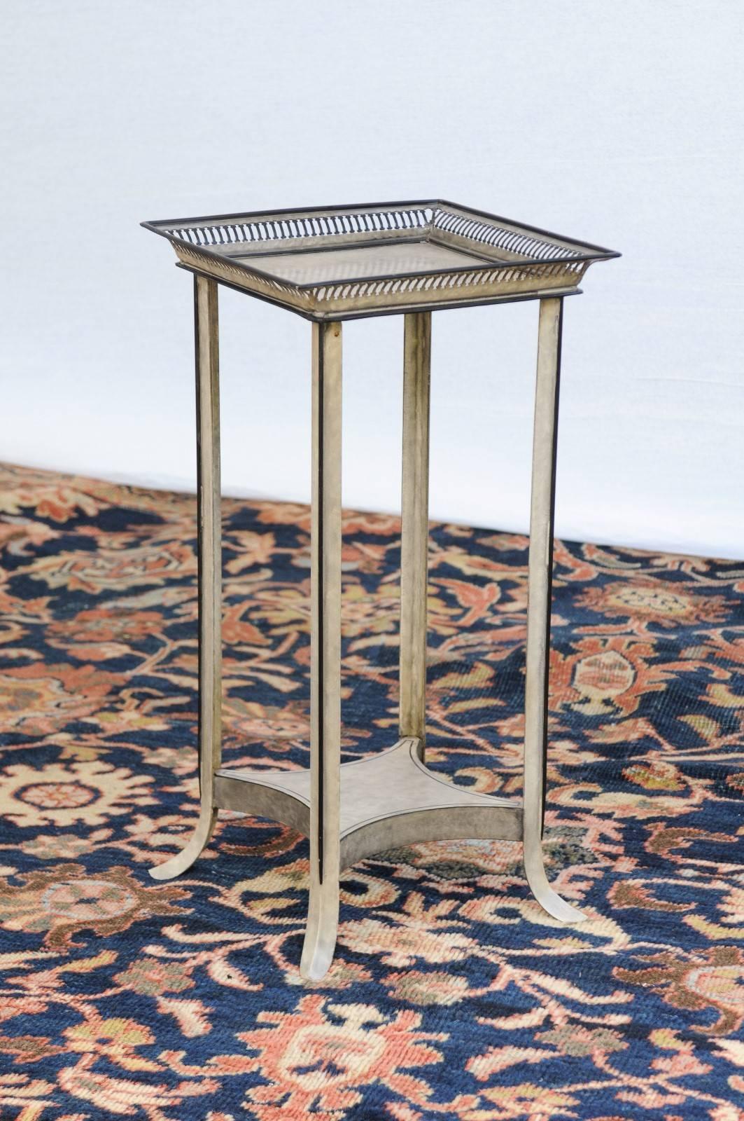 This delicate French painted tole table with painted trim, circa 1970 features a square tray top, four flared legs and a lower shelf. The top is adorned with a pierced gallery that creates a lightness that is furthered by the simple elegance of the