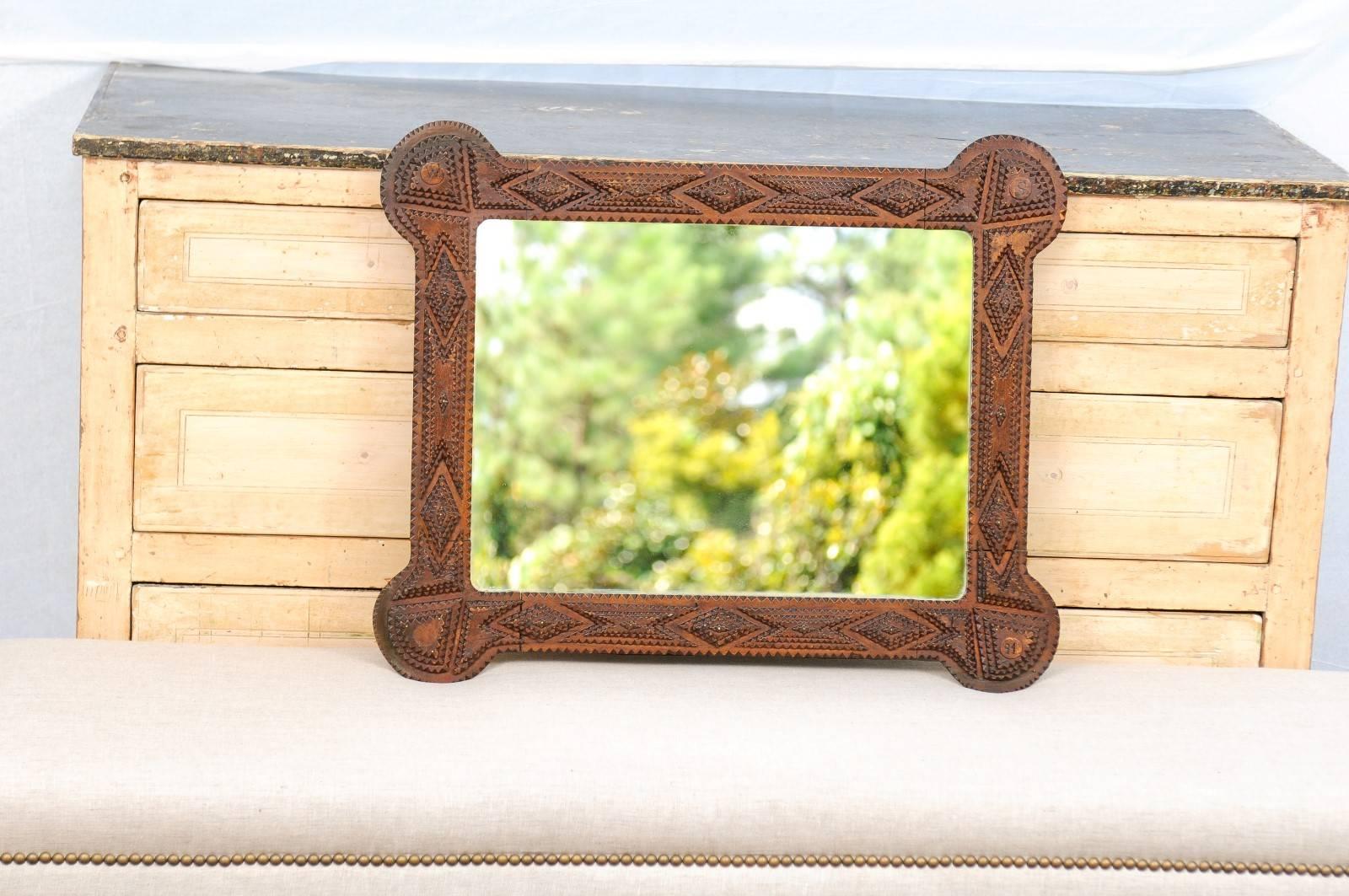 This French small size oak Tramp Art mirror from the turn of the century can be placed vertically or horizontally. The frame, made of layered notches and featuring diamond and triangle shapes, is nicely softened in its regularity by the rounded