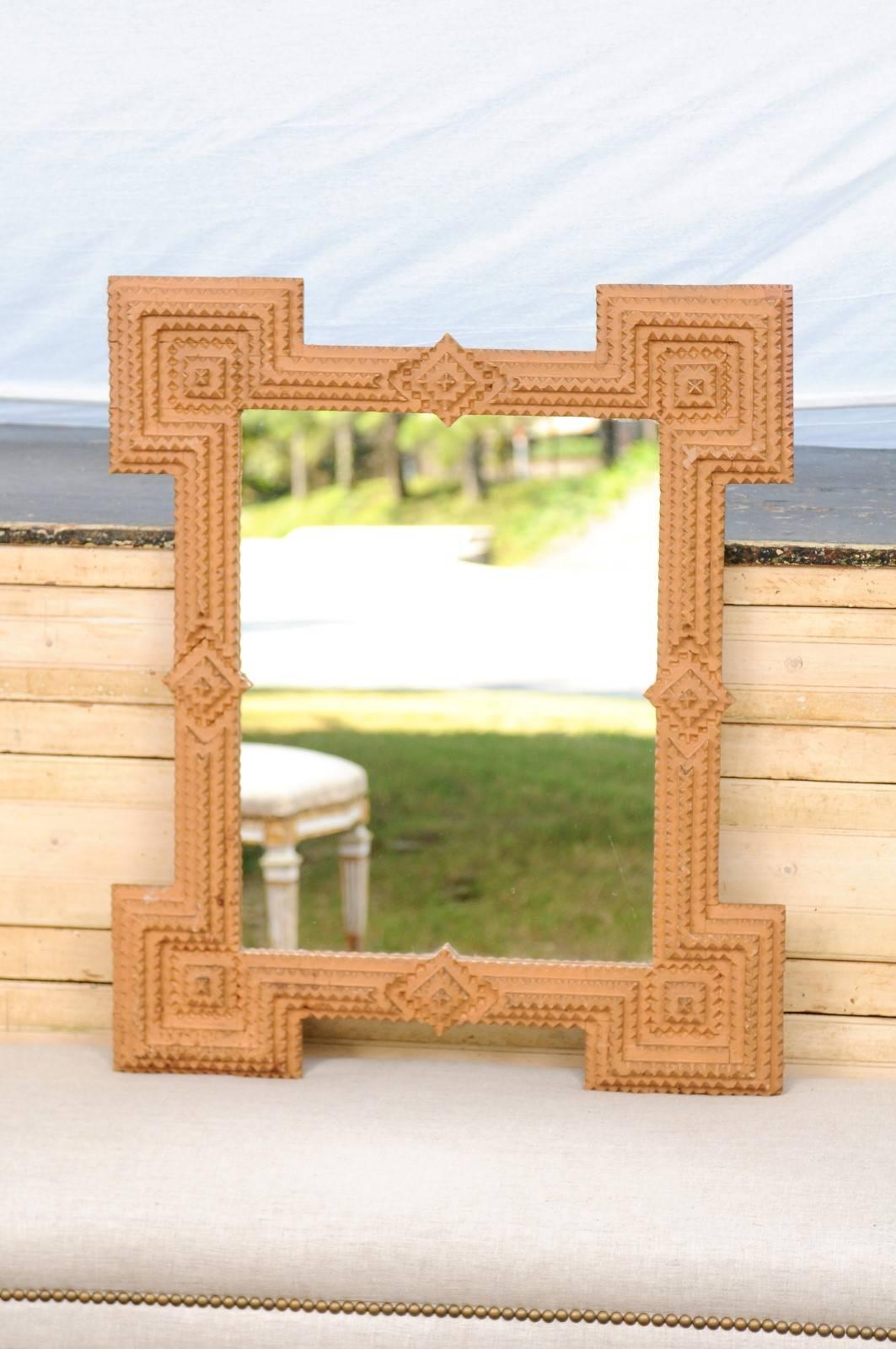 This French painted terracotta tramp art mirror from the early 20th century features the typical tramp art Silhouette: very linear, the frame is made of layered notches with geometrical shapes. Each corner of the mirror is adorned with a partial